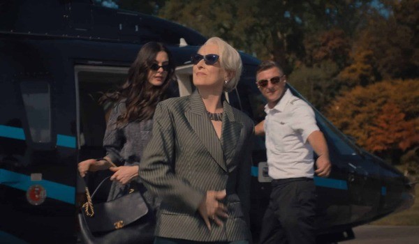Three fashionable people exiting a private helicopter, including a woman in a striped blazer and sunglasses, representing luxury travel and high-end lifestyle.